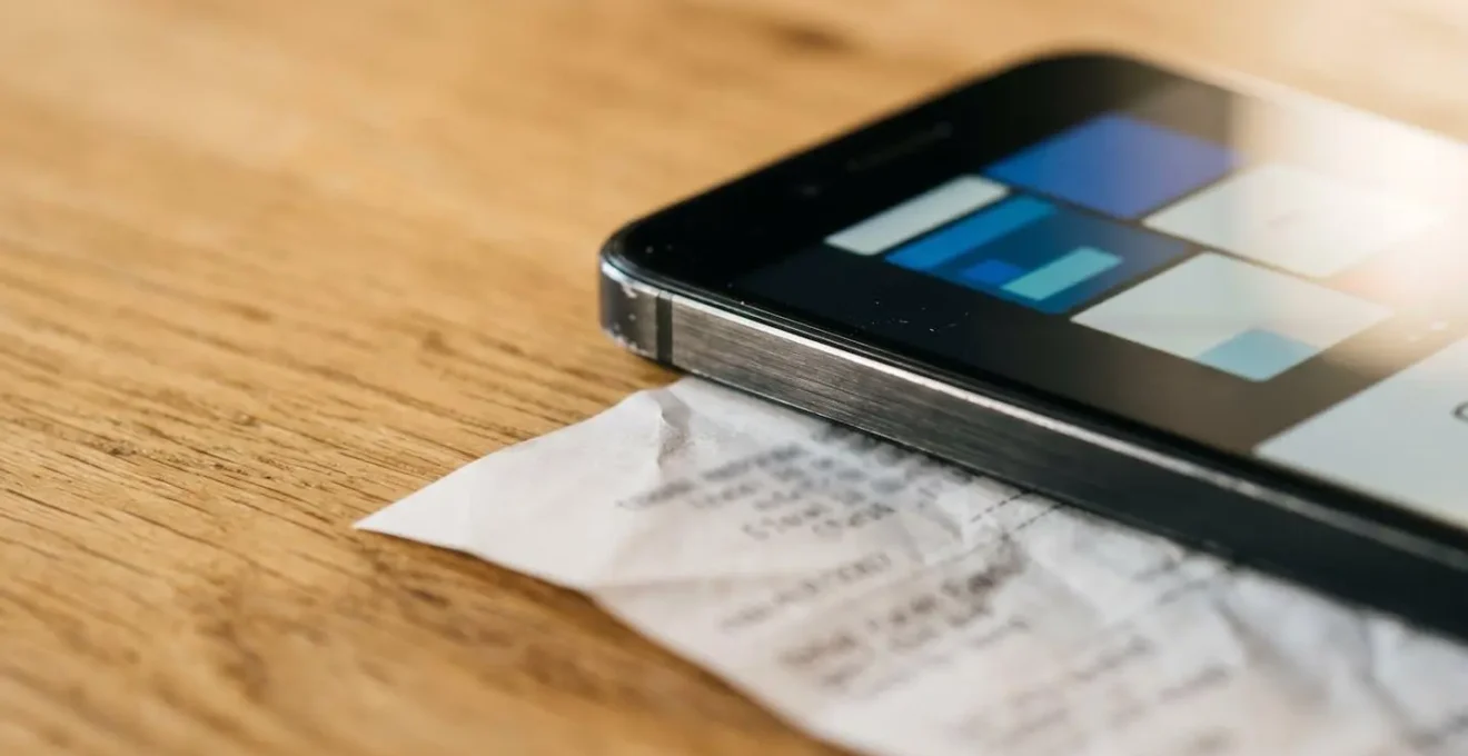 Close-up of smartphone camera capturing itemized healthcare receipt on wooden table with natural lighting