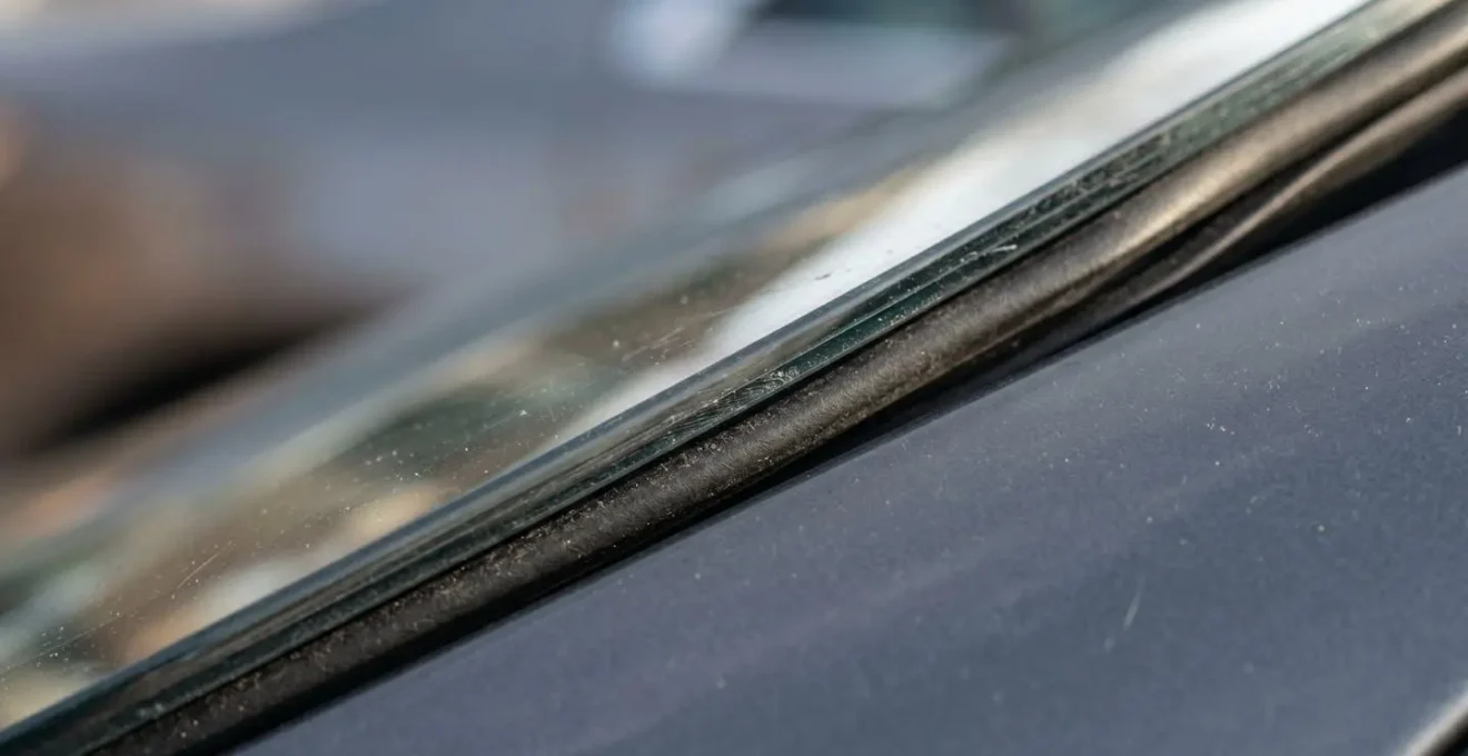 A close-up photograph showing the vulnerable edge of a car's windscreen and a tire tread, areas often excluded from standard car rental insurance.